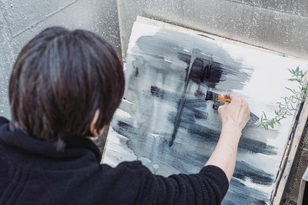 A painter in black doing an abstract painting