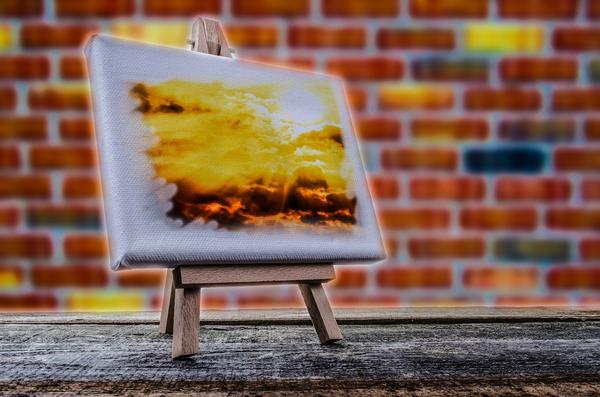 A painting of sunset with yellow clouds placed on an easel