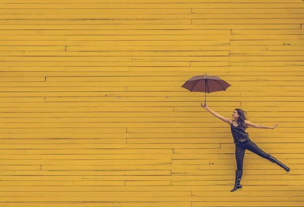 A photo of a woman at arms length with an umbrellas stretched out